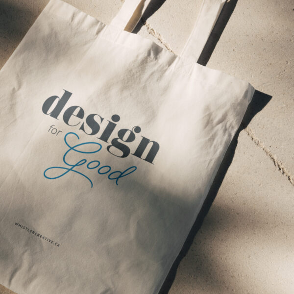 Canvas tote bag with "design for good" typography on it, resting on a concrete surface.