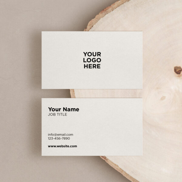 Two business cards on a wood surface, one face-up and one face-down. The face-up card displays placeholders for a logo, name, job title, email, phone number, and website, perfect for your next promotion.